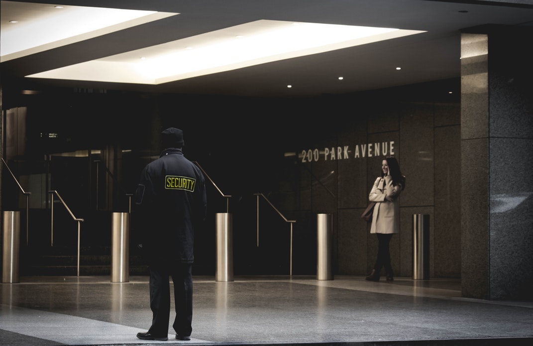 Security guard looking at a woman in a large public building
