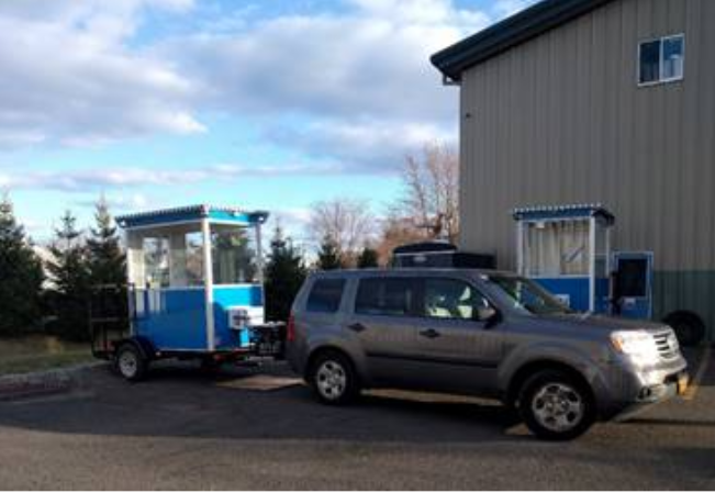 A blue guard booth being pulled by a truck