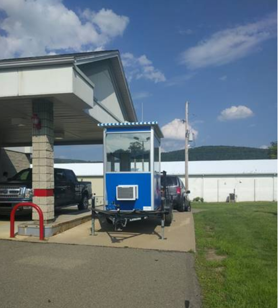 A blue trailer guard booth being pulled by a van