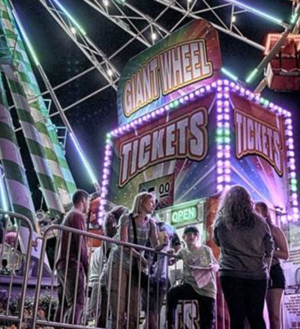 A neon lit ticket booth at an amusement park