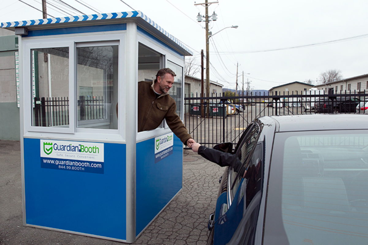 Parking booth outside an enclosed parking lot being manned by an attendant