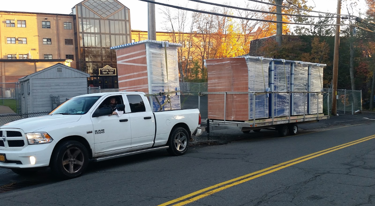 Shrink wrapped blue ticket booths being towed by a truck Shrink wrapped blue ticket booths being towed by a truck