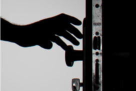 A hand reaching for a locked door with a key in it