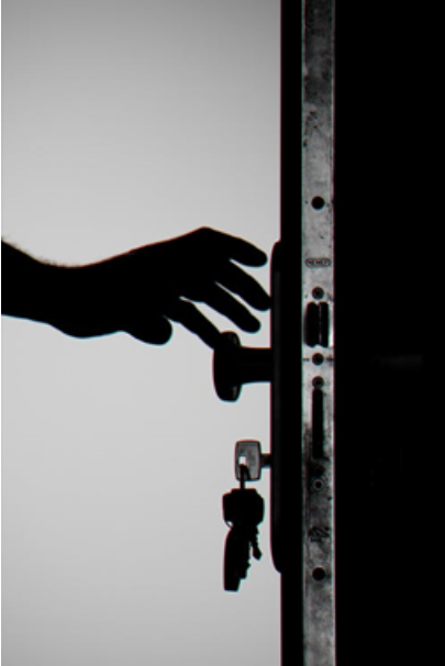 A hand reaching for a locked door with a key in it