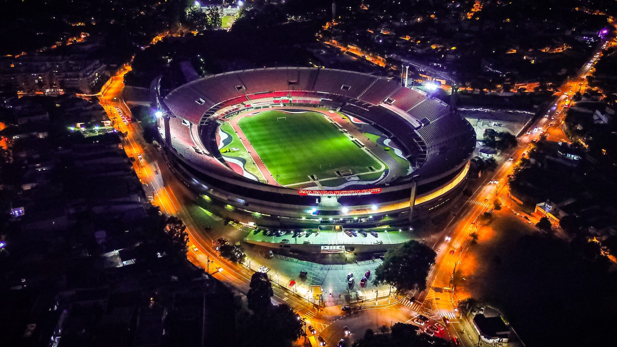 A large stadium lit up at night, as seen from above