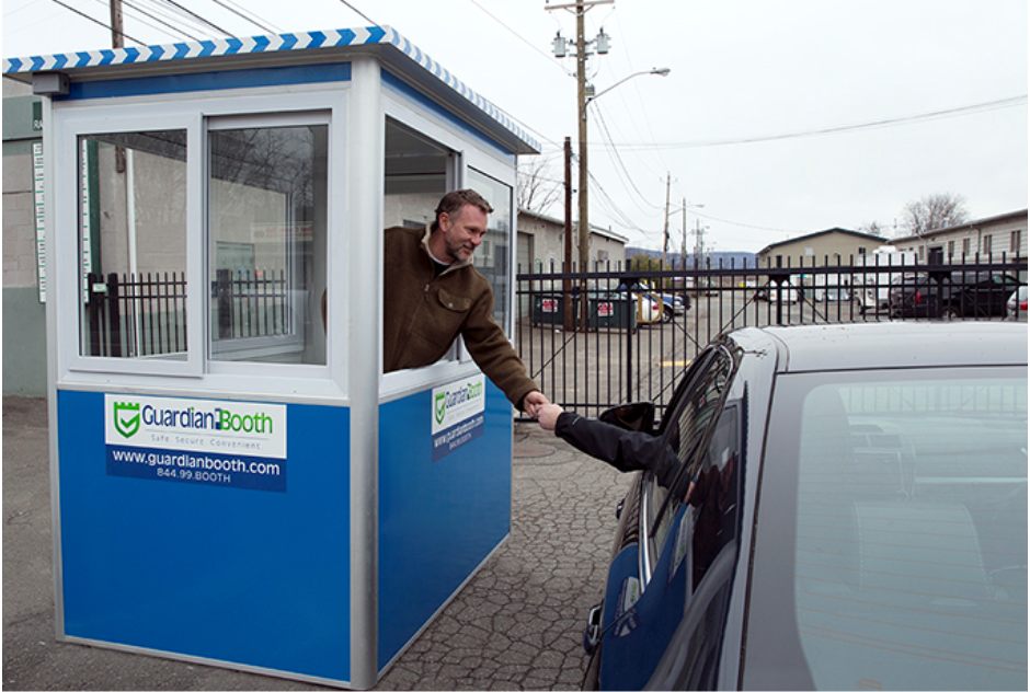 A man working in a blue parking booth, helping a customer