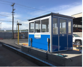 A blue guard booth on a cement foundation