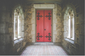 A stone hallway with a red door