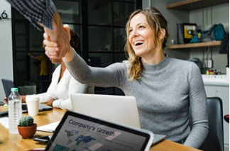 A woman at a computer reaching out to shake hands