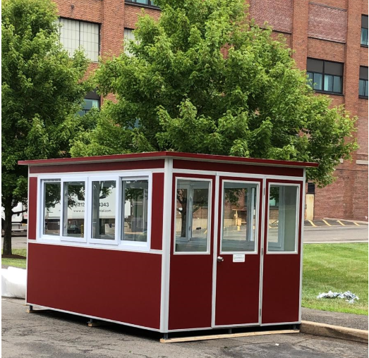 A large red guard shack in front of a school building