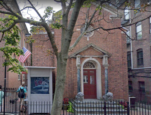 A small guard shack in front of a brick building