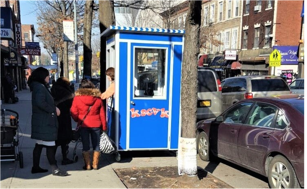 Guard booth on sidewalk with people around it