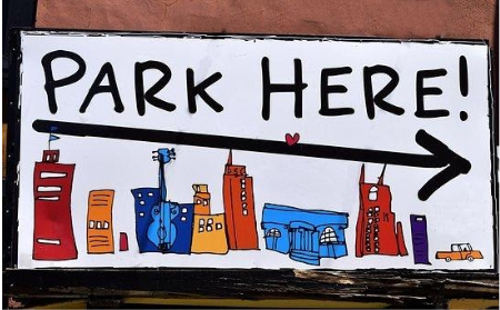 Sign that says Park Here, with cartoon buildings