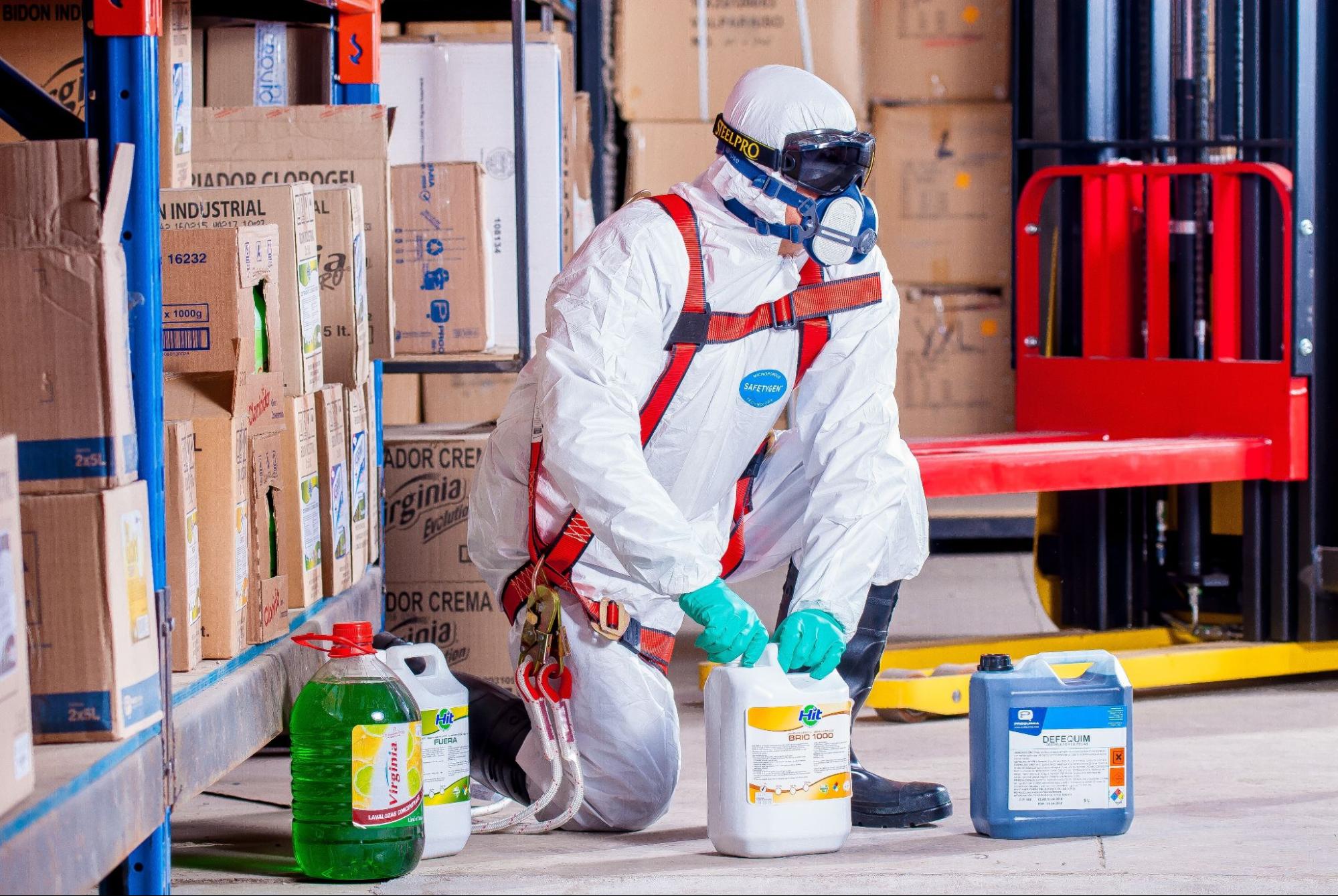 Worker handling chemicals with full protective clothing