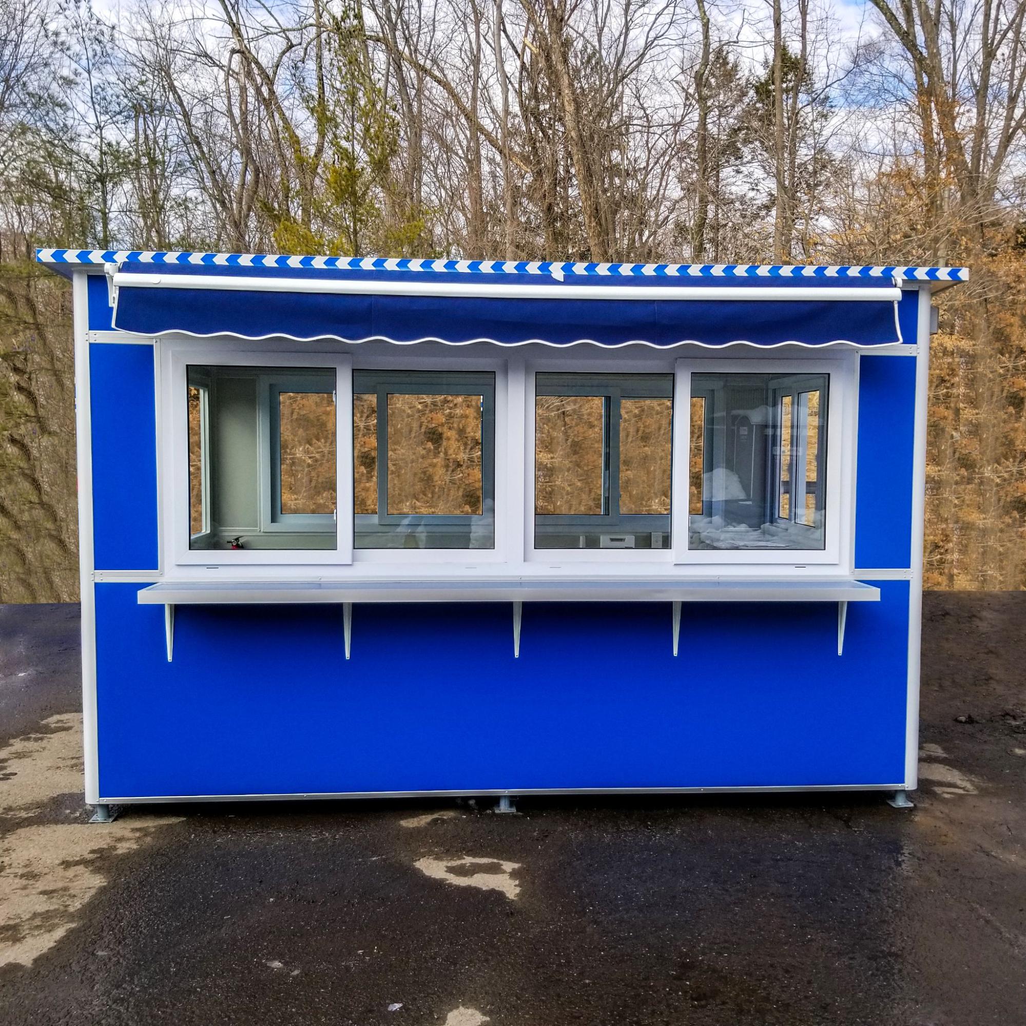 A blue prefabricated booth featuring large sliding windows and a striped roll-up awning