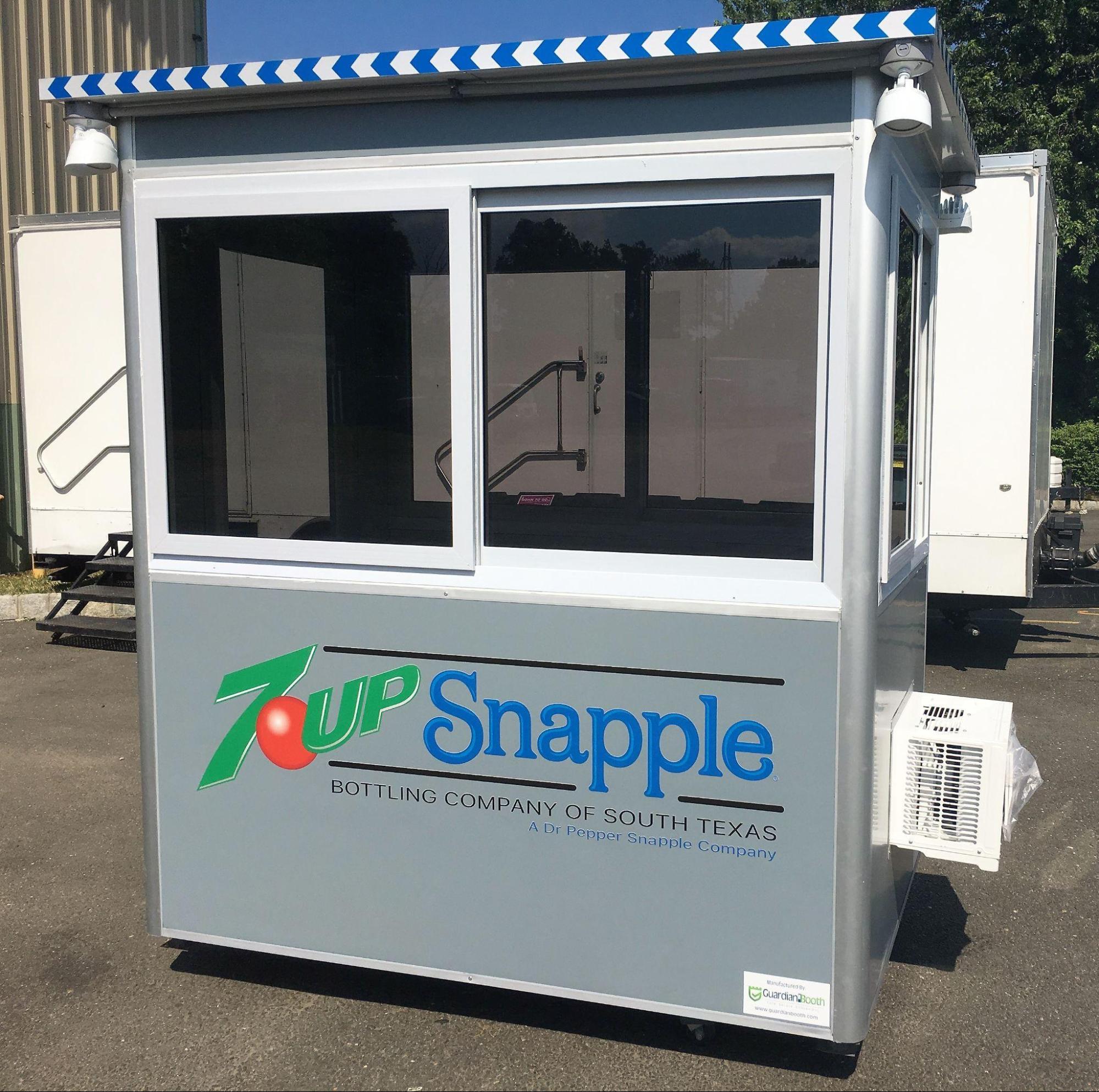 A grey prefabricated security guard booth branded with 7Up and Snapple logos