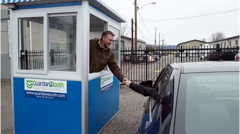 A-man-working-in-a-blue-parking-booth-helping-a-customer