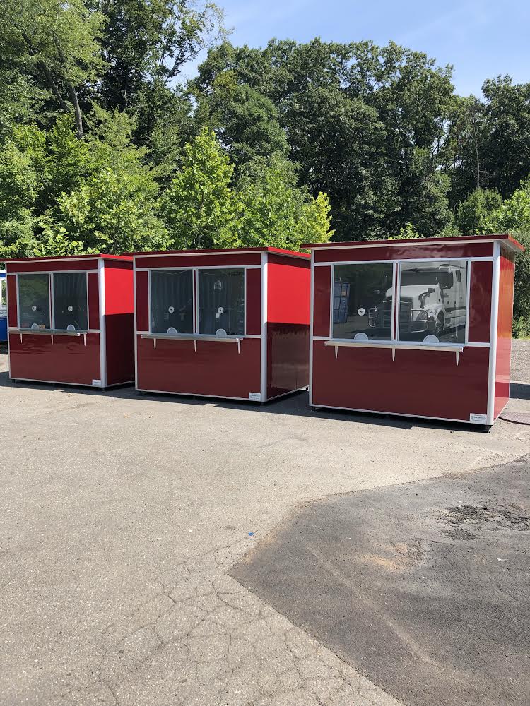 Three red prefab customer service booths featuring large windows, microphones, and counters