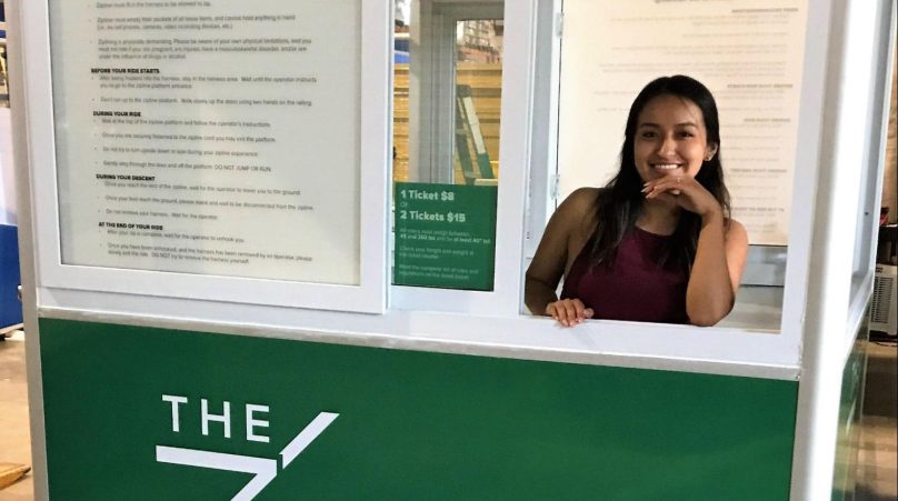 A green modular booth with a large sliding service window displays information to customers